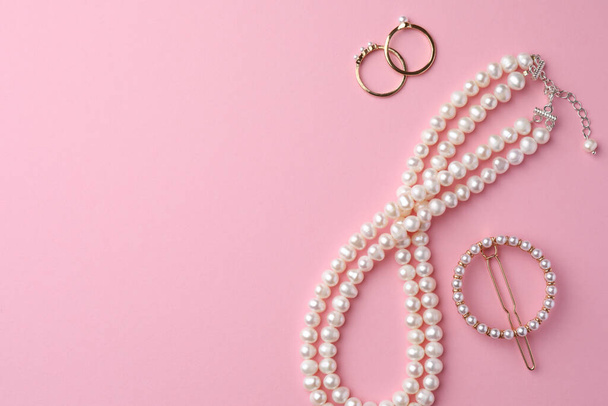 Elegant pearl jewelry on pink background, flat lay. Space for text - Foto, immagini