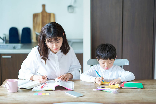 Uma mãe estudando em seu quarto e uma criança brincando ao lado dela - Foto, Imagem