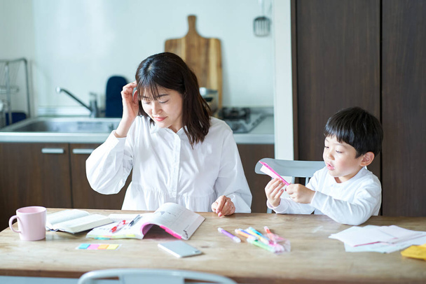 Uma mãe estudando em seu quarto e uma criança brincando ao lado dela - Foto, Imagem