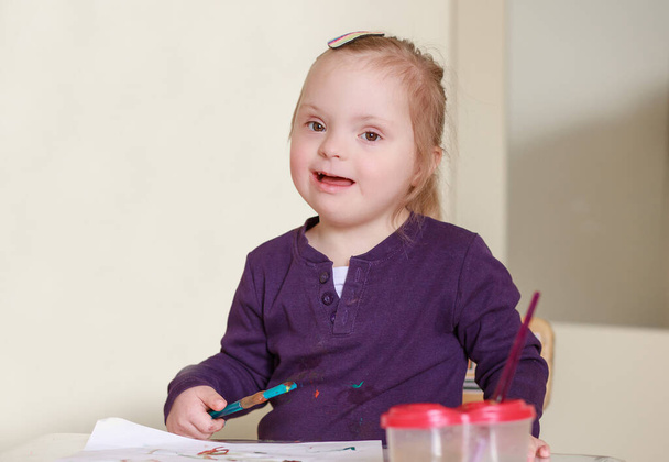 Uma menina com síndrome de Down desenha em um álbum com aquarelas. Desenvolvimento infantil através da criatividade. Artista. A menina aprende a desenhar com pinturas. - Foto, Imagem