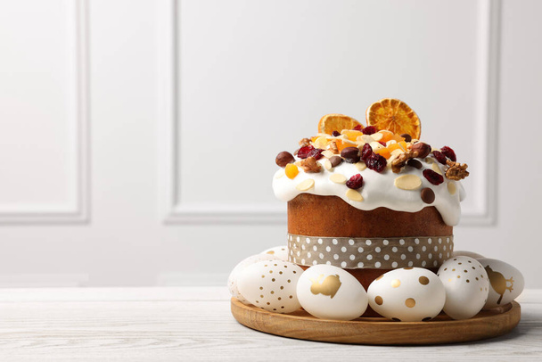 Traditional Easter cake with dried fruits and decorated eggs on white wooden table indoors. Space for text - Foto, Bild