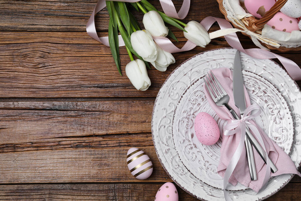 Festive table setting with painted eggs and tulips, flat lay with space for text. Easter celebration - 写真・画像