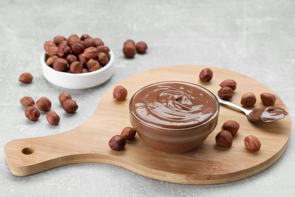 Bowl with tasty chocolate paste and nuts on light grey table - Φωτογραφία, εικόνα