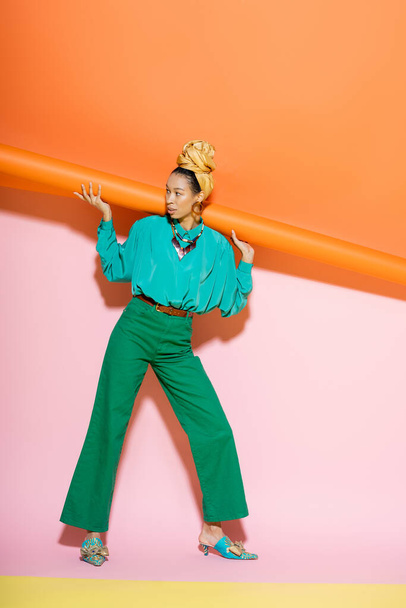 Fashionable african american woman in headscarf and bright outfit posing on colorful background  - Foto, Bild