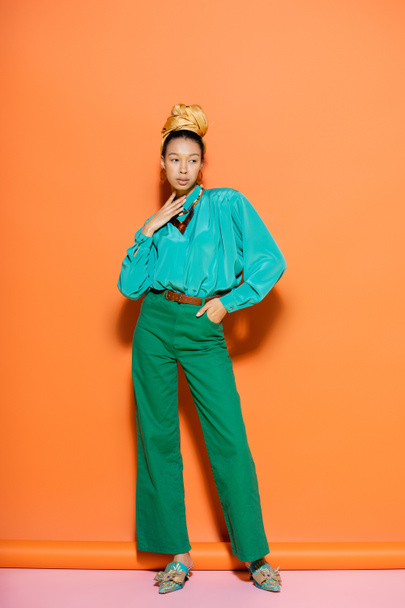 Full length of fashionable african american model in summer clothes looking away on orange and pink background  - Zdjęcie, obraz