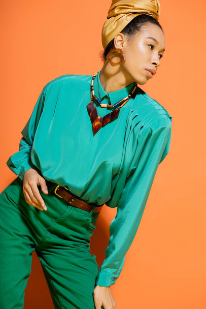 Trendy african american model in headscarf and blouse looking away on orange background  - Φωτογραφία, εικόνα