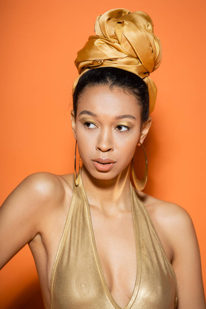 Trendy african american model in headscarf and swimsuit standing on orange background  - Photo, Image