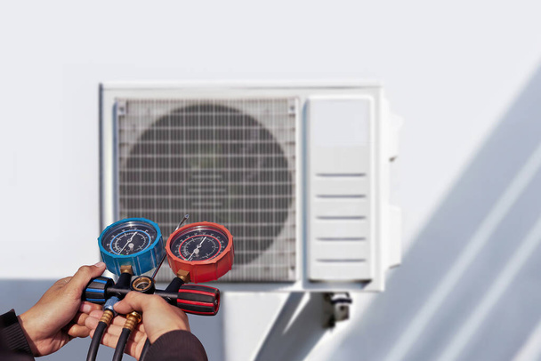 Klimaanlage, Klimatechniker mit Manometern, um Kältemittel zu überprüfen und Kältemittel hinzuzufügen. - Foto, Bild