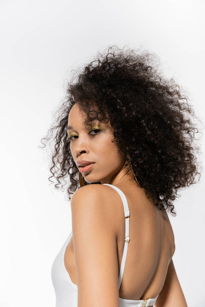 african american model with curly hair posing in white swimsuit isolated on grey  - Photo, Image