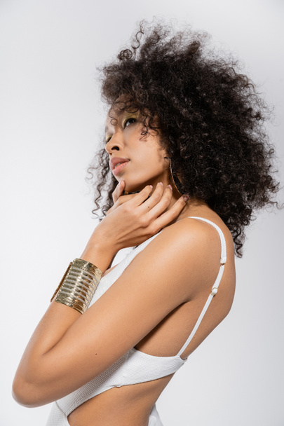 pretty african american woman with golden bracelet posing isolated on grey  - 写真・画像