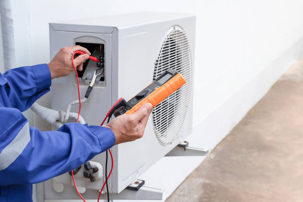 Légkondicionáló, HVAC szerviztechnikus mérőműszerekkel ellenőrzi a hűtőközeget és hűtőközeget ad hozzá. - Fotó, kép