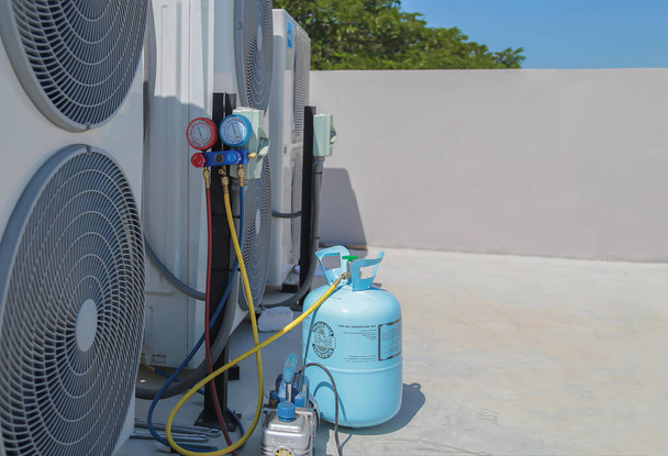 ilmastointi, LVI-huoltoteknikko, joka käyttää mittareita kylmäaineen tarkistamiseen ja kylmäaineen lisäämiseen. - Valokuva, kuva