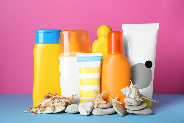 Different suntan products, seashells and starfishes on color background - 写真・画像