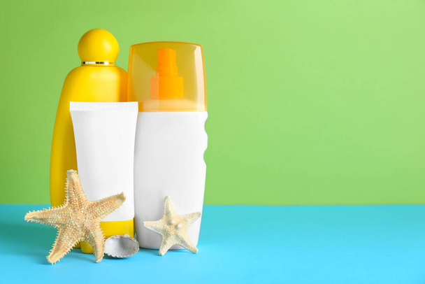 Different suntan products and starfishes on color background. Space for text - 写真・画像