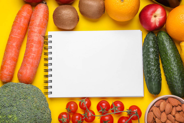 Notizbuch, frisches Obst und Gemüse auf gelbem Hintergrund, flach gelegt. Diät mit niedrigem glykämischen Index - Foto, Bild