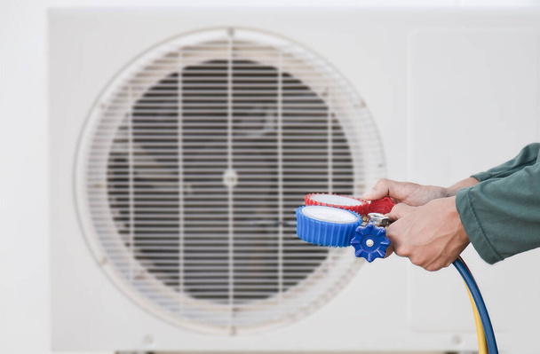 Aire acondicionado, técnico de servicio de climatización que utiliza medidores para comprobar el refrigerante y añadir refrigerante. - Foto, imagen