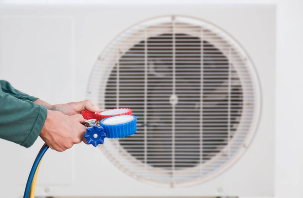 Aire acondicionado, técnico de servicio de climatización que utiliza medidores para comprobar el refrigerante y añadir refrigerante. - Foto, imagen