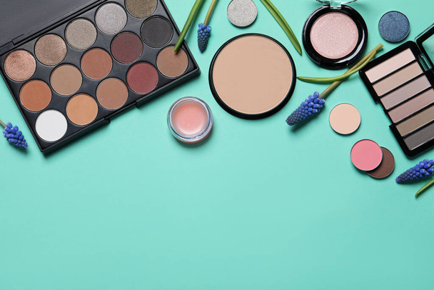 Flat lay composition with eyeshadow palettes and beautiful flowers on turquoise background, space for text - Valokuva, kuva