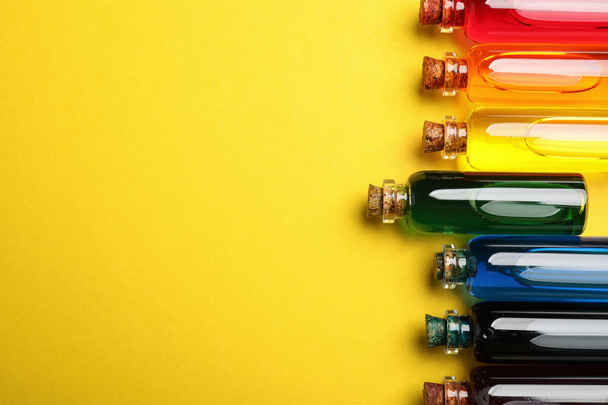 Bottles with different food coloring on yellow background, flat lay. Space for text - Zdjęcie, obraz