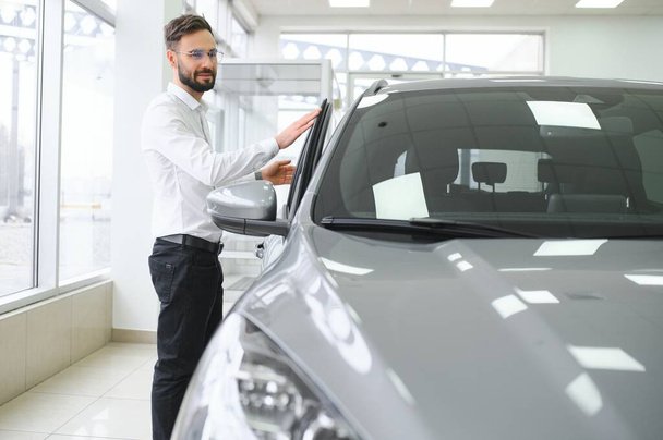 a man examines a car in a car dealership. - Фото, зображення