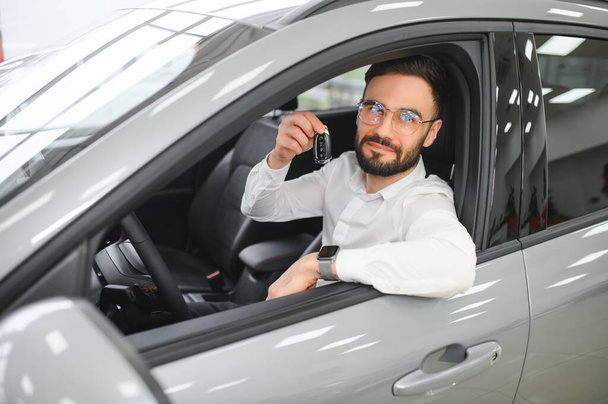 Happy caucasian man in formal wear getting inside luxury modern car for testing interior before purchase. Concept of dealership, selling and purchase. - Foto, imagen