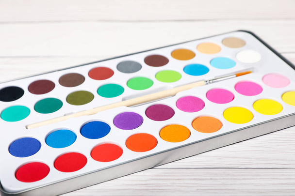 Watercolor palette with brush on white wooden table, closeup - Photo, Image