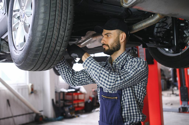 Auto mechanic working at auto repair shop. - Фото, изображение