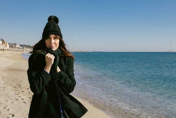 Frau mit Hut und Mantel am Strand an einem sonnigen Wintertag - Foto, Bild