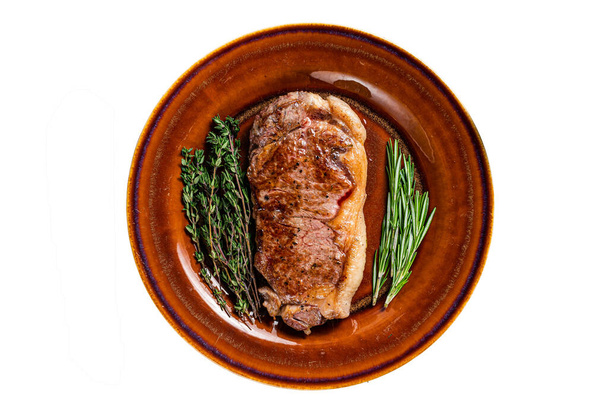 Geroosterde vlees steak of striploin in een rustieke schotel. Geïsoleerd op witte achtergrond - Foto, afbeelding