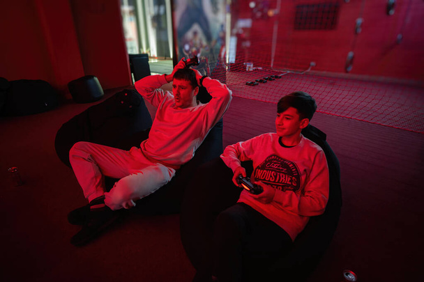 Oh no, i'm lost! Father and son play gamepad video game console in red gaming room. Dad and kid gamers. - Foto, immagini