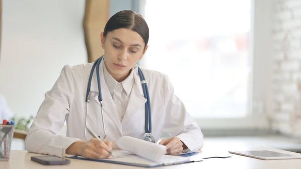 Young Female Doctor Working on Medical Report in Clinic - Photo, Image