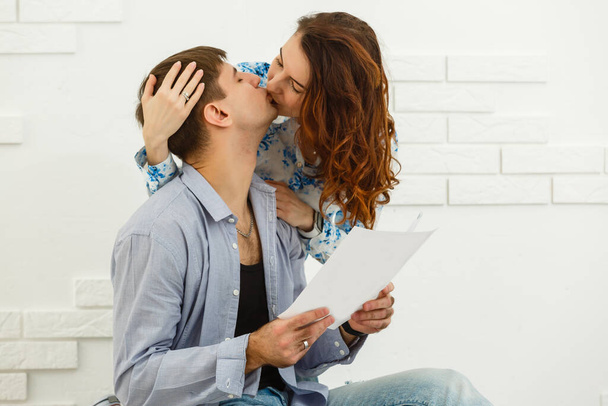 Lächelnd sitzen Mann und Frau und kümmern sich um Versorgungsrechnungen und Hauswartpapiere, glückliches junges Paar liest Papierkram. - Foto, Bild