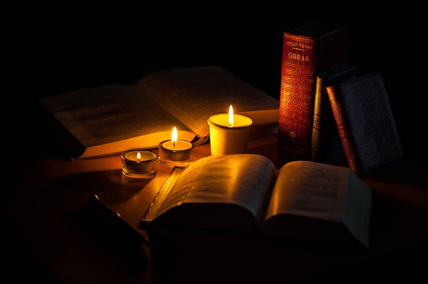 старые книги со свечой на черном фоне - Фото, изображение