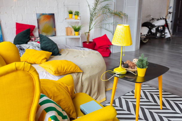 Trendy fashion luxury interior design in Scandinavian style of studio apartment with bright yellow furniture and decorated with new year lights. - 写真・画像