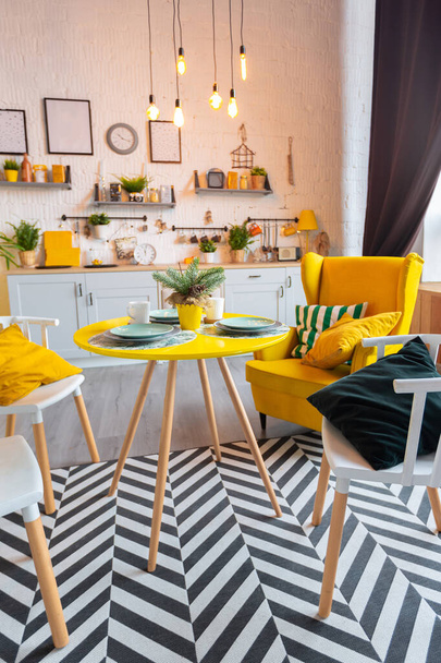 Trendy fashion luxury interior design in Scandinavian style of studio apartment with bright yellow furniture and decorated with new year lights. - Photo, Image