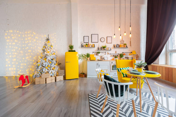 Divatos divat luxus belsőépítészet skandináv stílusú stúdió apartman világos sárga bútorokkal és díszített újévi fények. - Fotó, kép