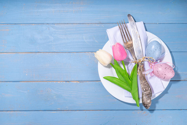 Easter table setting with tulip flowers and eggs, tag with text Happy Easter, over light blue wooden background top view copy space - Valokuva, kuva