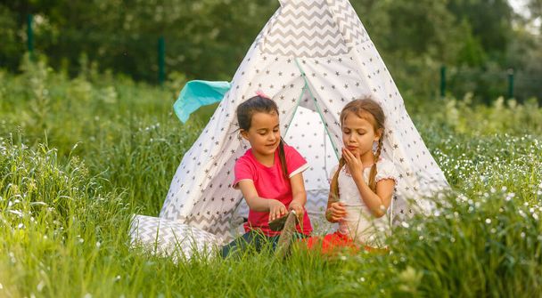 детство и хигге концепция - счастливые маленькие девочки играют в детской палатке. - Фото, изображение