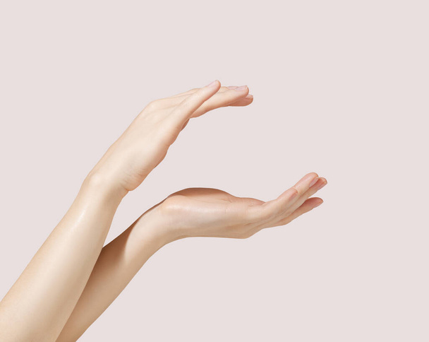 Modelo de mano sosteniendo un frasco cosmético sobre un fondo rosa para publicidad cosmética - Foto, Imagen