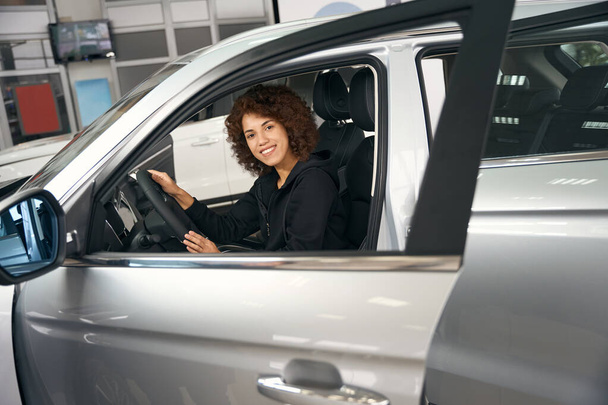 Happy multiracial shopper sits in the salon of a brand new car, she chooses the right model - Foto, Imagem