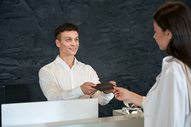 Homme à la table de service à la clientèle remise certificat à la femme avec de l'argent dans le salon de spa - Photo, image