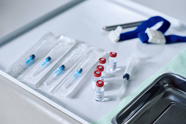 Κοντινό πλάνο συσκευασμένων συριγγών και φιαλών με φάρμακα στο τραπέζι που προετοιμάζονται για εμβολιασμό από τον ιό - Φωτογραφία, εικόνα