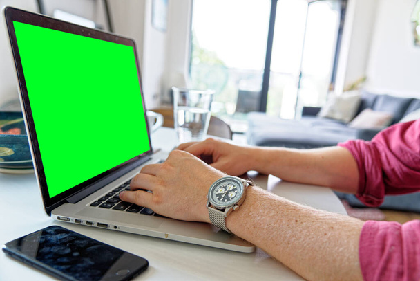 Nuori ammattilainen käyttää kannettavaa vihreällä näytöllä - yllään muoti katsella. Työ kotoa - Lontoo, Yhdistynyt kuningaskunta, 1. kesäkuuta 2019 - Valokuva, kuva