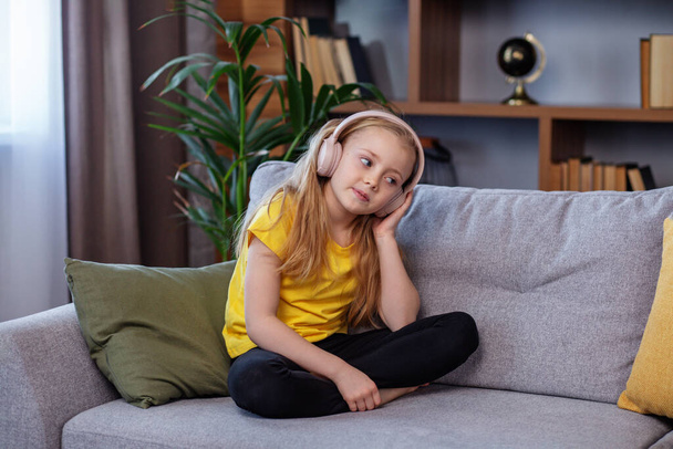 Ευτυχισμένο παιδί ακούει μουσική ή ηχητικό βιβλίο. Ένα σχολιαρόπαιδο με ακουστικά. Η μουσική μου φτιάχνει τη μέρα - Φωτογραφία, εικόνα