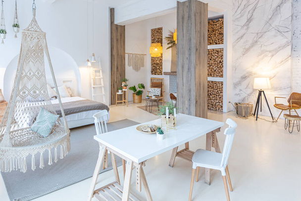 Intérieur moderne à la mode d'un studio lumineux avec colonnes en bois dans le style loft, décoré avec brique, marbre et bois avec des meubles élégants et des murs blancs - Photo, image