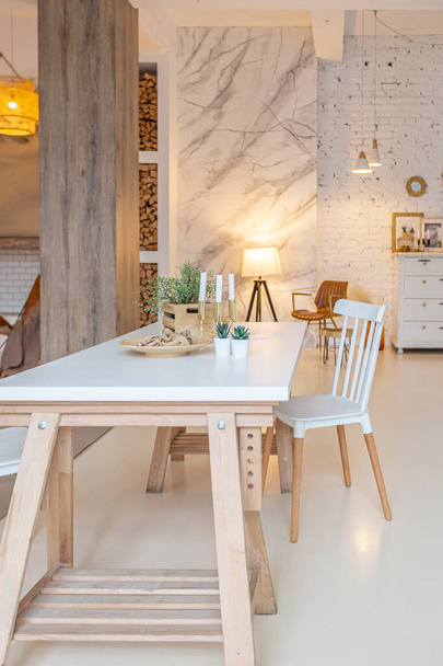 Fashionable modern interior of a light studio apartment with wooden columns in the loft style, decorated with brick, marble and wood with stylish furniture and white walls - Foto, imagen