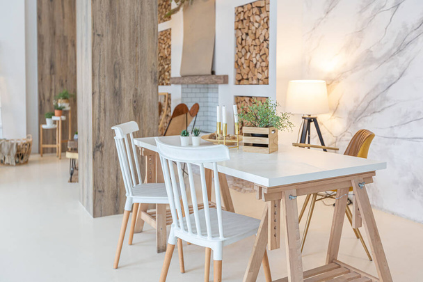 Fashionable modern interior of a light studio apartment with wooden columns in the loft style, decorated with brick, marble and wood with stylish furniture and white walls - 写真・画像