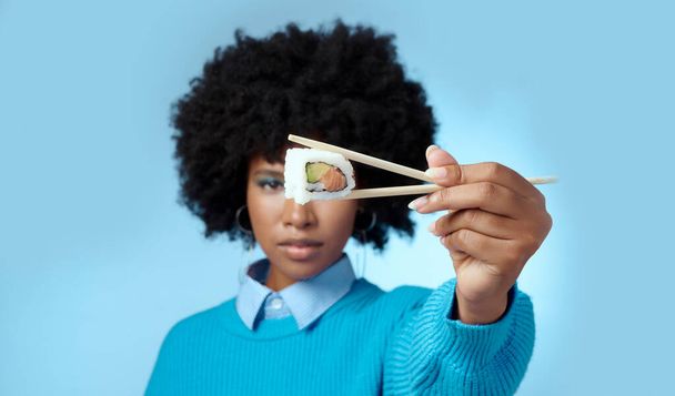Yemek, stüdyo ve portrede suşisi olan siyah bir kadın Japon diyetini sadece maket alanla yiyorlar. Sağlıklı, sahte ve aç Afrikalı bir kız elinde Asya yemek çubuklarıyla deniz ürünleri tutuyor.. - Fotoğraf, Görsel