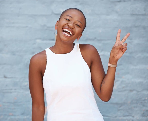 Portret, ręka i znak pokoju z biznesową czarną kobietą na ścianie z niebieskiej cegły z uśmiechem. Ręka, emoji i motywacja z pracownicą wykazującą gest v jednocześnie czując się pozytywnie lub pewnie. - Zdjęcie, obraz