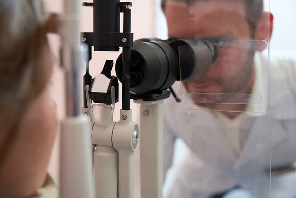 Nahaufnahme Porträt des Arztes untersucht Sehkraft mit Spezialgerät in Augenklinik - Foto, Bild